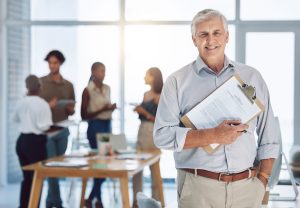 older worker with clipboard in office