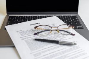 Resume paper on laptop with eyeglasses and pen, job interview and resume view